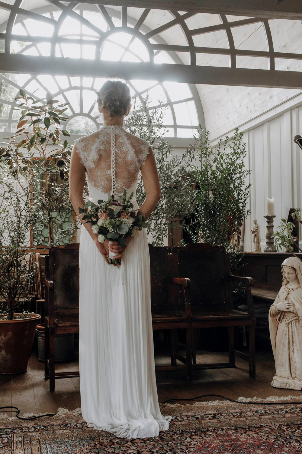 Braut vor einem Blumenarrangement in der Kapelle