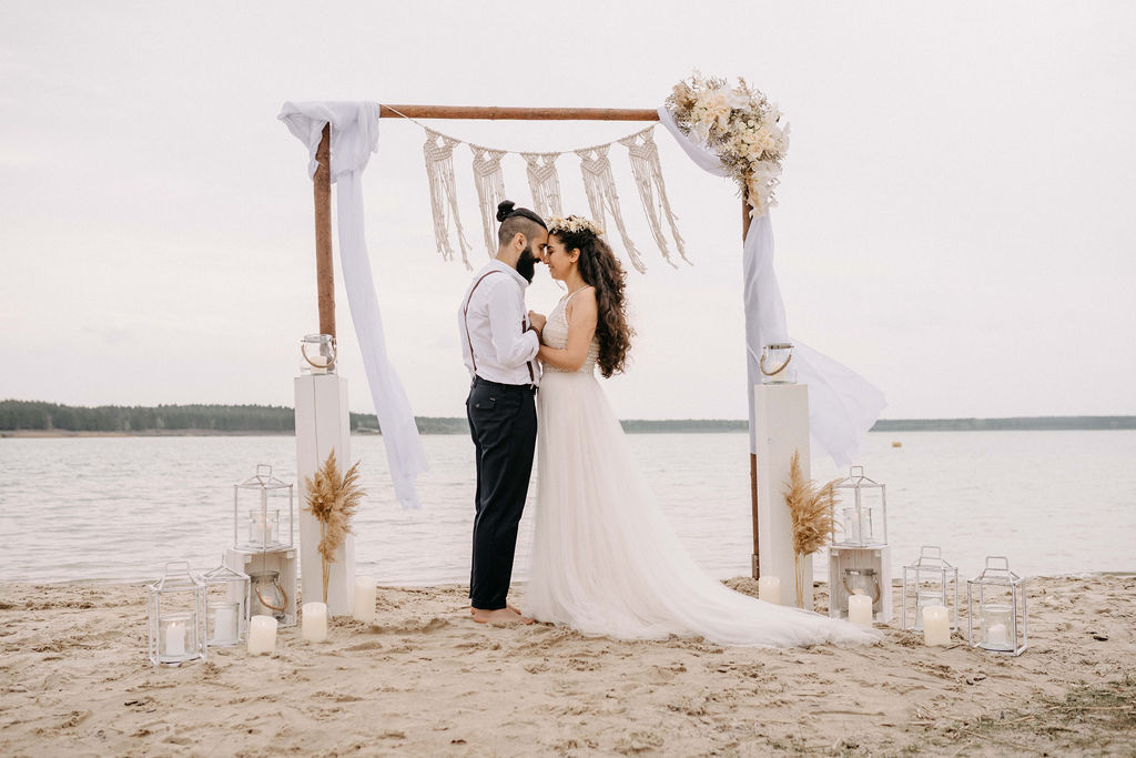 Brautpaar mit Strandkulisse und Deko im Bohostil