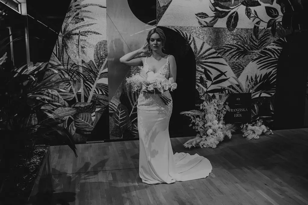 Braut posiert vor Blumendekoration mit Brautstrauß